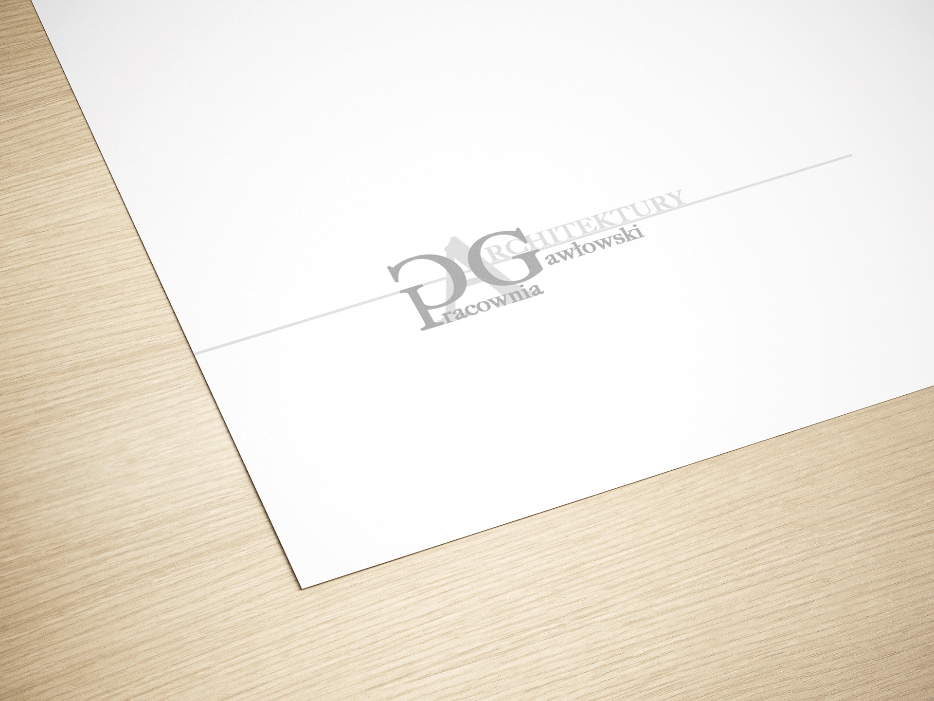 Projekt logo pracowni architektonicznej DG na białym papierze leżącym na drewnianym blacie, z widocznym cieniem i delikatnym oświetleniem.