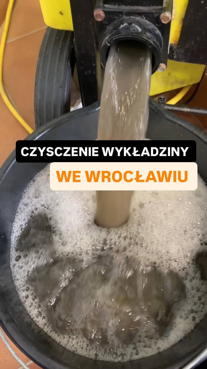 Woda z detergentem i brudem spływa do wiadra z maszyny do czyszczenia wykładzin. Widoczne bąbelki i resztki zanieczyszczeń. Czyszczenie wykładzin we Wrocławiu.