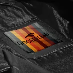 Wnętrze czarnej skórzanej kurtki z wszytą metką z logo 'GOOSEFLESH' na tle kolorowych pionowych pasków.