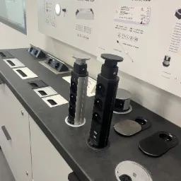 Blat z wbudowanymi gniazdkami elektrycznymi i portami USB, prezentowany na tle ekspozycji oświetleniowej Master Slim, ukazujący detale nowoczesnych rozwiązań.