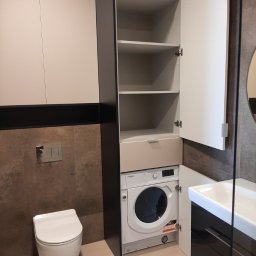 Mark Pol Meble - Nowoczesna łazienka z zabudową meblową: szafki wiszące, słupek z półkami, pralka w zabudowie, umywalka z szafką. Uwagę przykuwa spójna kolorystyka i funkcjonalne zagospodarowanie przestrzeni.