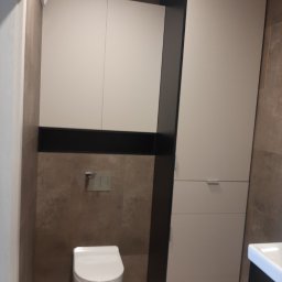 Mark Pol Meble - Minimalistyczna łazienka z zabudową meblową w odcieniach bieli i szarości. Wisząca toaleta, ciemne akcenty nad stelażem. Nowoczesny design.