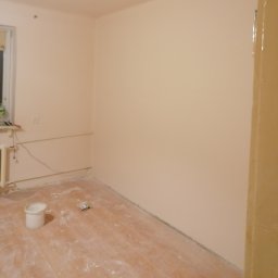 TSiD-tanio, szybko i dokladnie - Pomieszczenie po malowaniu ścian na jasny odcień, widoczny kubeł po farbie i zabrudzenia na podłodze.