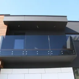 Nowoczesny budynek z drewnianą i grafitową elewacją, szklana balustrada balkonu z punktowym mocowaniem