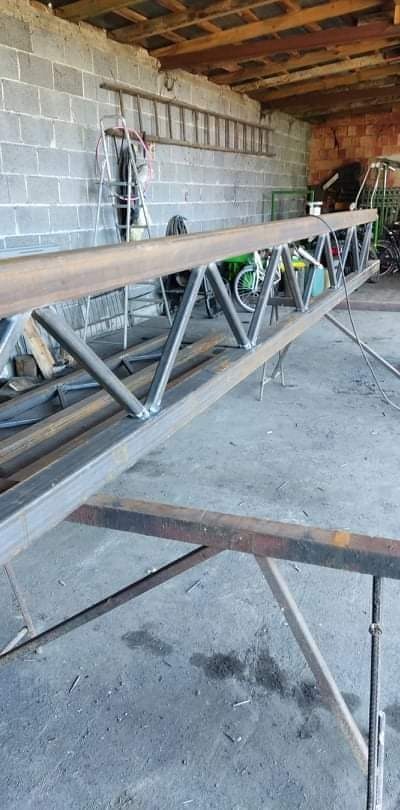 Stalowa kratownica spawana z rur, ustawiona na warsztatowym stole, widoczne ślady spawania i surowy wygląd metalu.