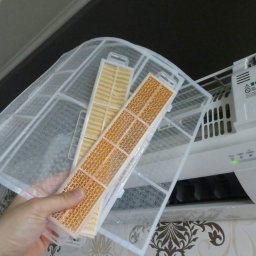 I-Klimat sp. z o.o. - Filtr powietrza klimatyzatora, z widocznymi zabrudzeniami, wyjmowany do czyszczenia, na tle białej jednostki wewnętrznej z zieloną diodą.