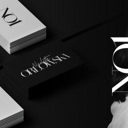 Patryk Markowski - Stos wizytówek z eleganckim, kaligraficznym logo na czarnym tle, uzupełniony o stos białych wizytówek. Minimalistyczny design z elementami typografii.