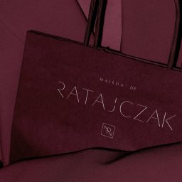 Patryk Markowski - markovsky.co - Bordowa torba papierowa z logo 'Maison de Ratajczak' na tle bordowej tkaniny. Minimalistyczny design, elegancki detal identyfikacji wizualnej marki.