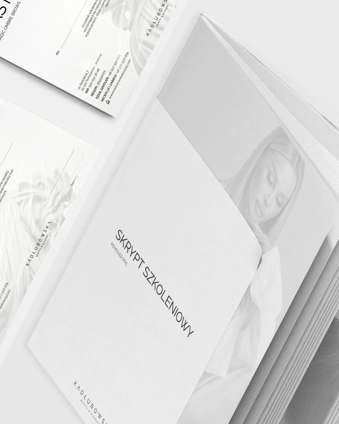 Biały skrypt szkoleniowy REMOVER PML marki Kadłubowska Beauty & Academy, otwarty na stronie z wizerunkiem kobiety, leży obok wizytówki firmy.