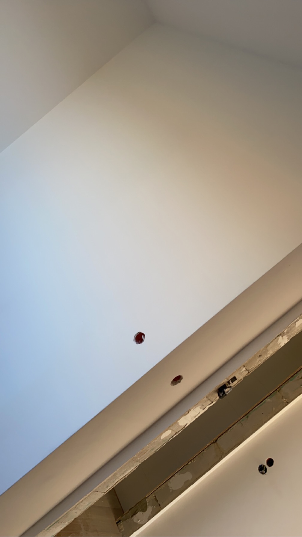 Niedokończona instalacja sufitu podwieszanego z widocznymi otworami na oświetlenie punktowe i odsłoniętą konstrukcją nośną