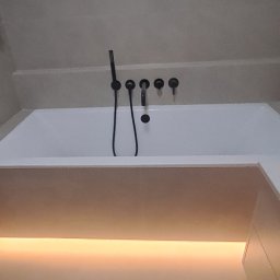 Dizajn Jarosław Lauer - Minimalistyczna łazienka: biała wanna z czarną armaturą i subtelnym podświetleniem LED. Nowoczesny design, stonowana kolorystyka, eleganckie wykończenie.