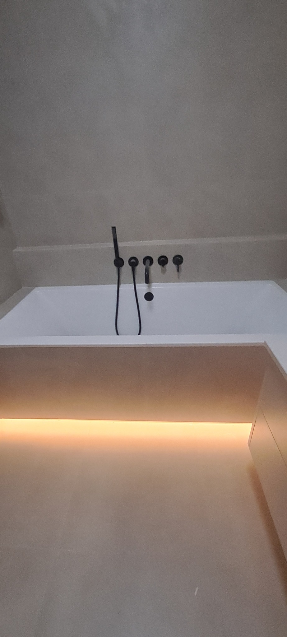 Minimalistyczna łazienka: biała wanna z czarną armaturą i subtelnym podświetleniem LED. Nowoczesny design, stonowana kolorystyka, eleganckie wykończenie.