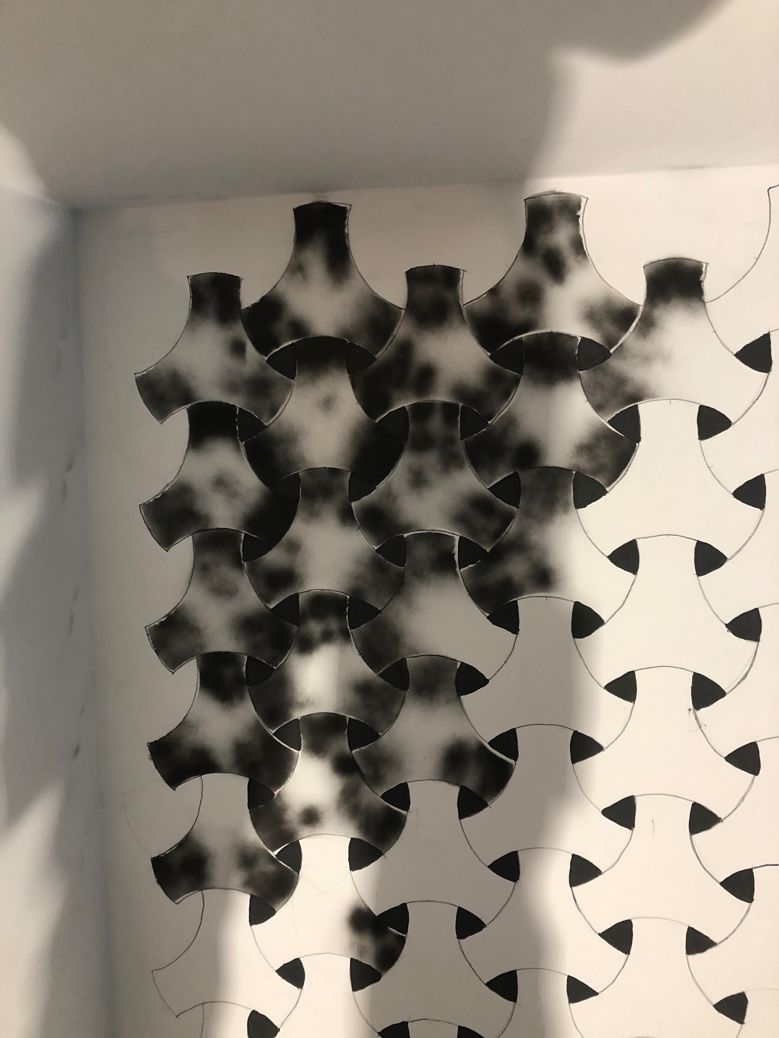 Ściana z geometrycznym wzorem wykonanym farbą w sprayu, częściowo zamalowana, widoczne linie pomocnicze.