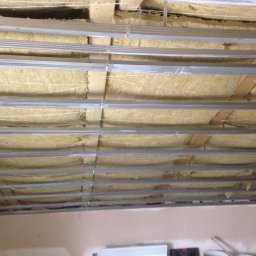 DAPO Firma Ogólnobudowlana - Sufit z widoczną izolacją z wełny mineralnej i metalową konstrukcją nośną, przygotowany do montażu płyt gipsowo-kartonowych.