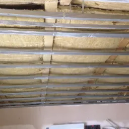 Sufit z widoczną izolacją z wełny mineralnej i metalową konstrukcją nośną, przygotowany do montażu płyt gipsowo-kartonowych.