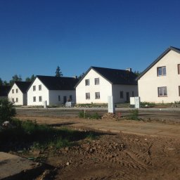 DAPO Firma Ogólnobudowlana - Rząd nowych, dwukondygnacyjnych domów z ciemnymi dachami i jasnymi elewacjami, w trakcie budowy, widoczny plac budowy i materiały budowlane.