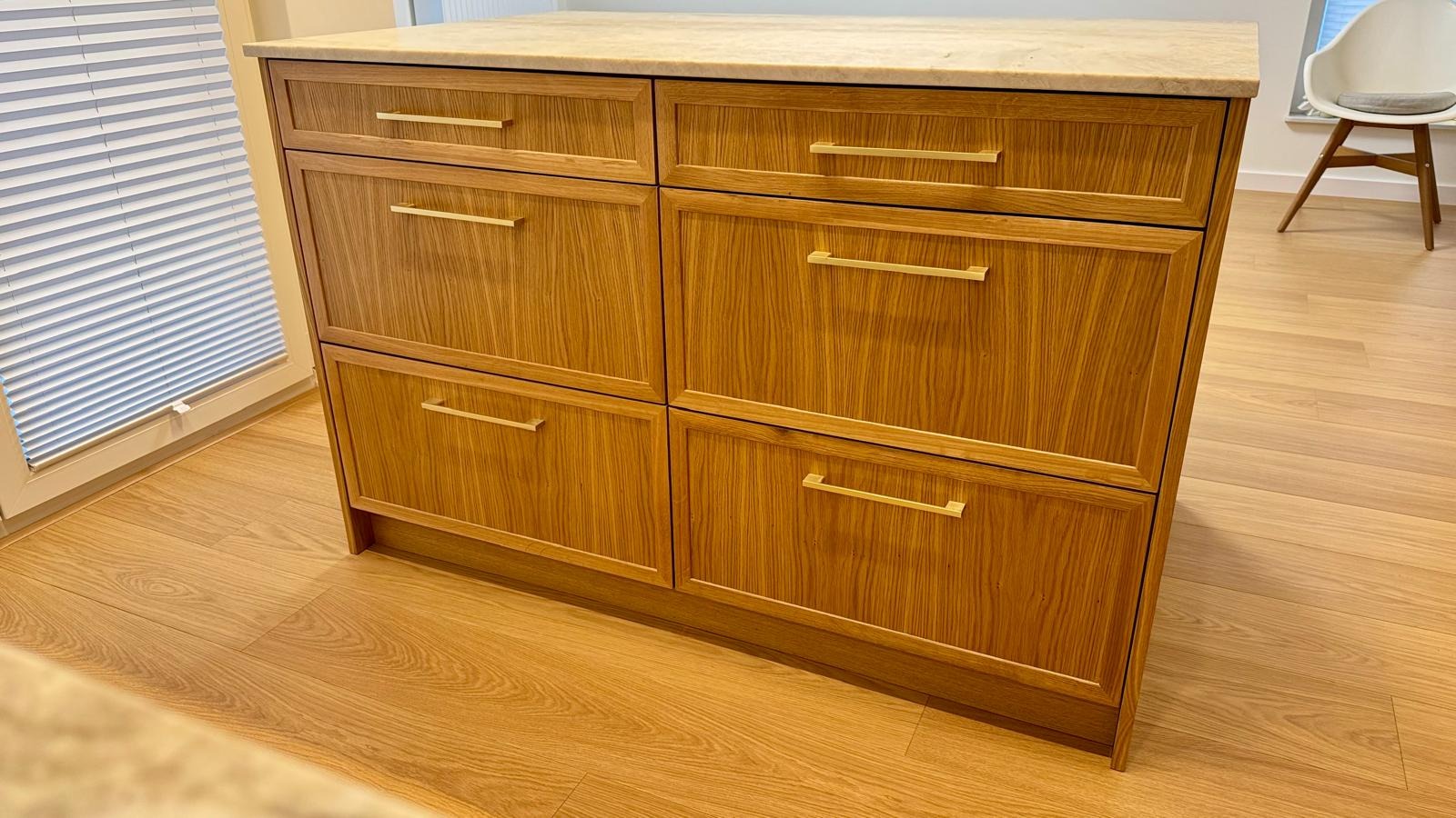 Drewniana komoda z sześcioma szufladami i marmurowym blatem, widoczna na tle okna z żaluzjami i krzesła.