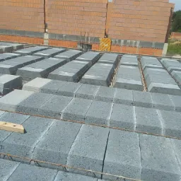 Wznoszenie ścian domu z bloczków silikatowych na stropie Teriva, z widoczną konstrukcją zbrojeniową i fragmentem drewnianej deski.