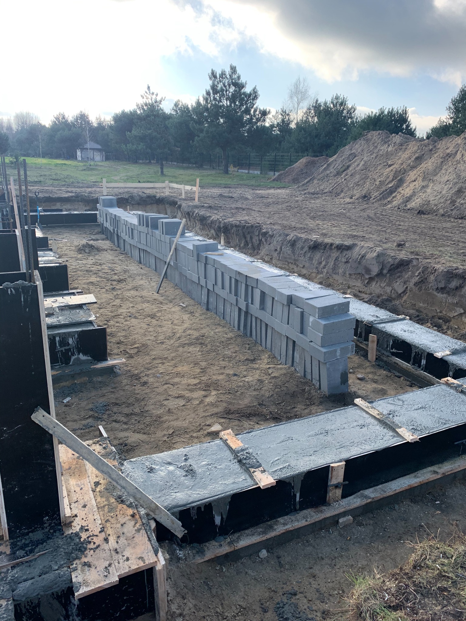 Wykonywanie fundamentów pod budynek z bloczków betonowych w Warszawie, widoczne szalunki i zbrojenia.