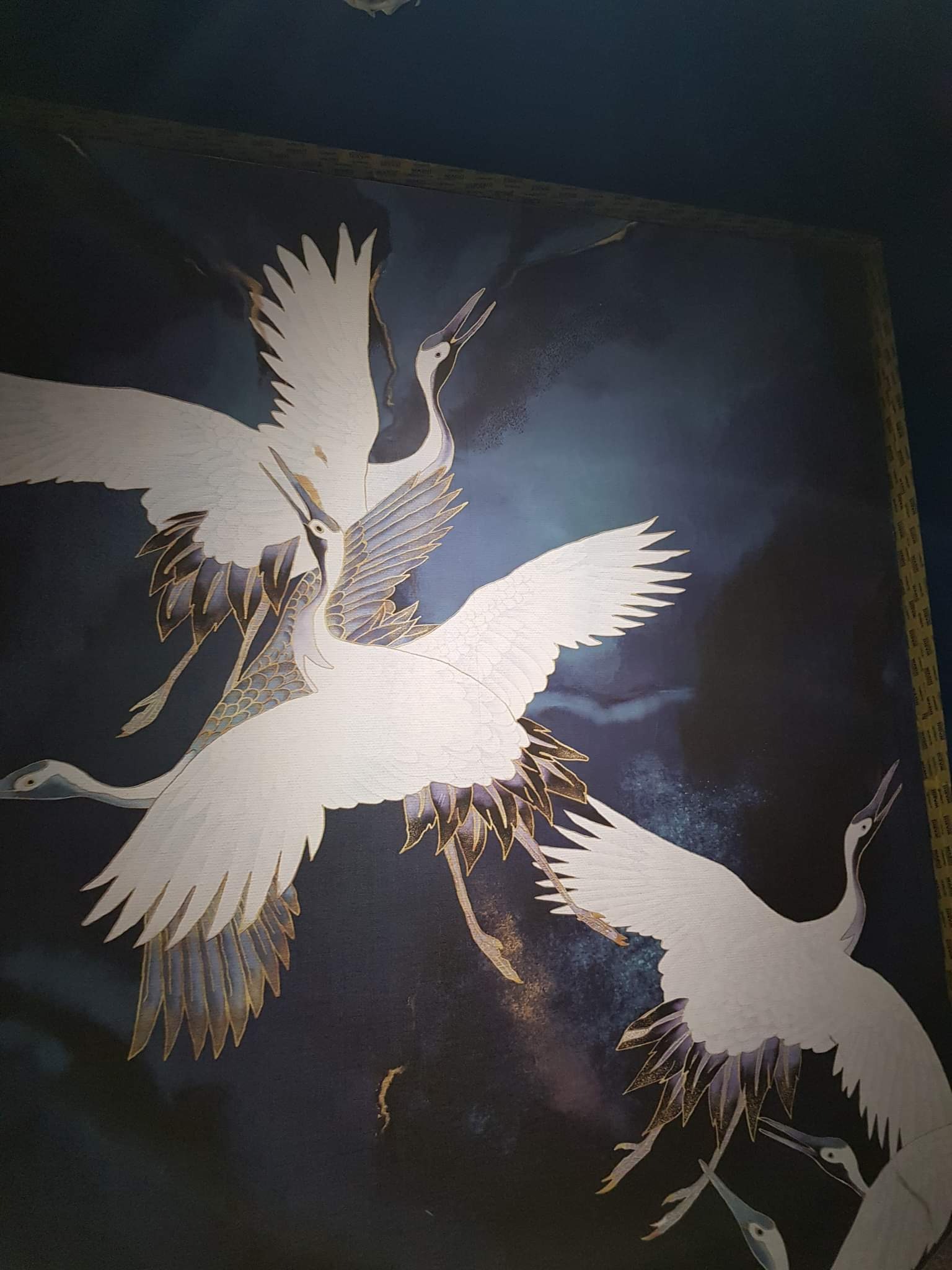 Tapeta z motywem żurawi w locie na ciemnym, abstrakcyjnym tle z delikatnymi, złotymi akcentami.