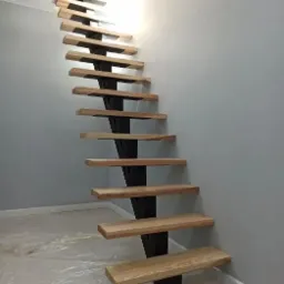 Nowoczesne schody z drewnianymi stopniami i metalową konstrukcją nośną, widok z dołu, podłoga zabezpieczona folią malarską.