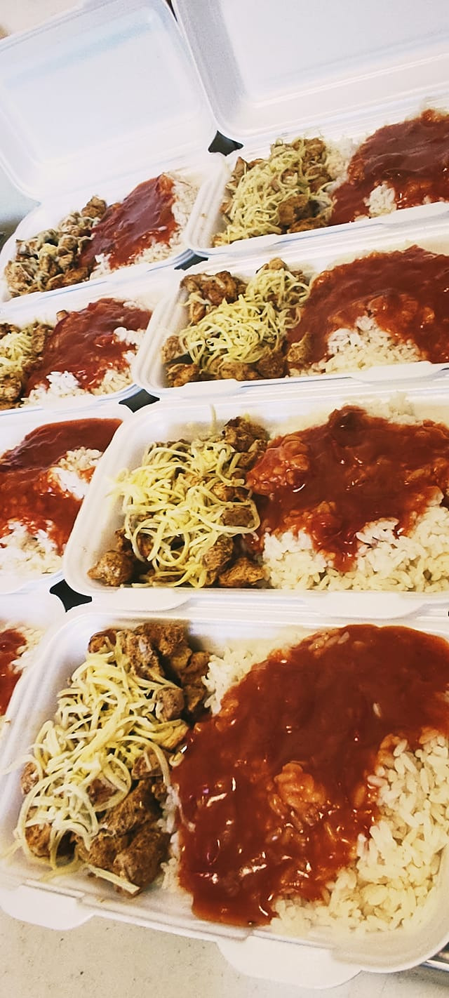 Porcje obiadowe w białych pojemnikach styropianowych: ryż polany sosem, mięso i makaron jajeczny.