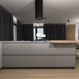 Nowoczesna kuchnia z szarymi frontami szafek, drewnianym blatem i czarnym okapem cylindrycznym, widok na salon z telewizorem i krzesłem barowym.