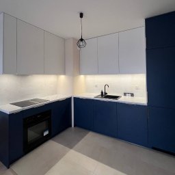 Meble Bruno spółka z o.o. - Nowoczesna kuchnia z białymi górnymi szafkami i granatowymi dolnymi, marmurowym blatem, czarnym zlewem i płytą indukcyjną, oświetleniem LED pod szafkami i geometryczną lampą wiszącą.