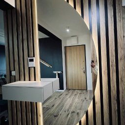 Owalne lustro na ścianie z lamelami