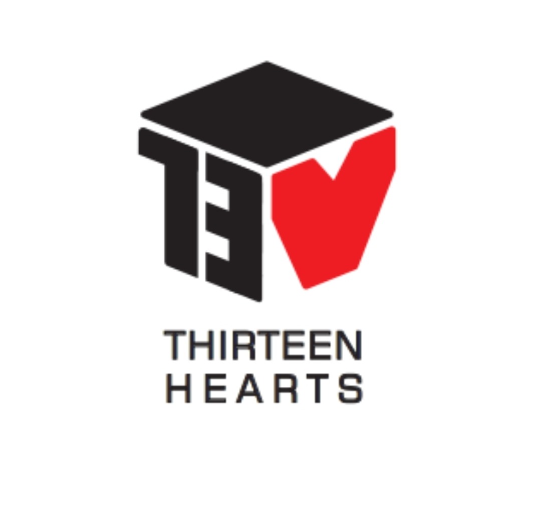 Graficzne logo firmy 'Thirteen Hearts' przedstawiające stylizowaną liczbę 13 w kolorze czarnym, wkomponowaną w trójwymiarowy sześcian z czerwonym sercem w prawym górnym rogu, umieszczone nad nazwą...