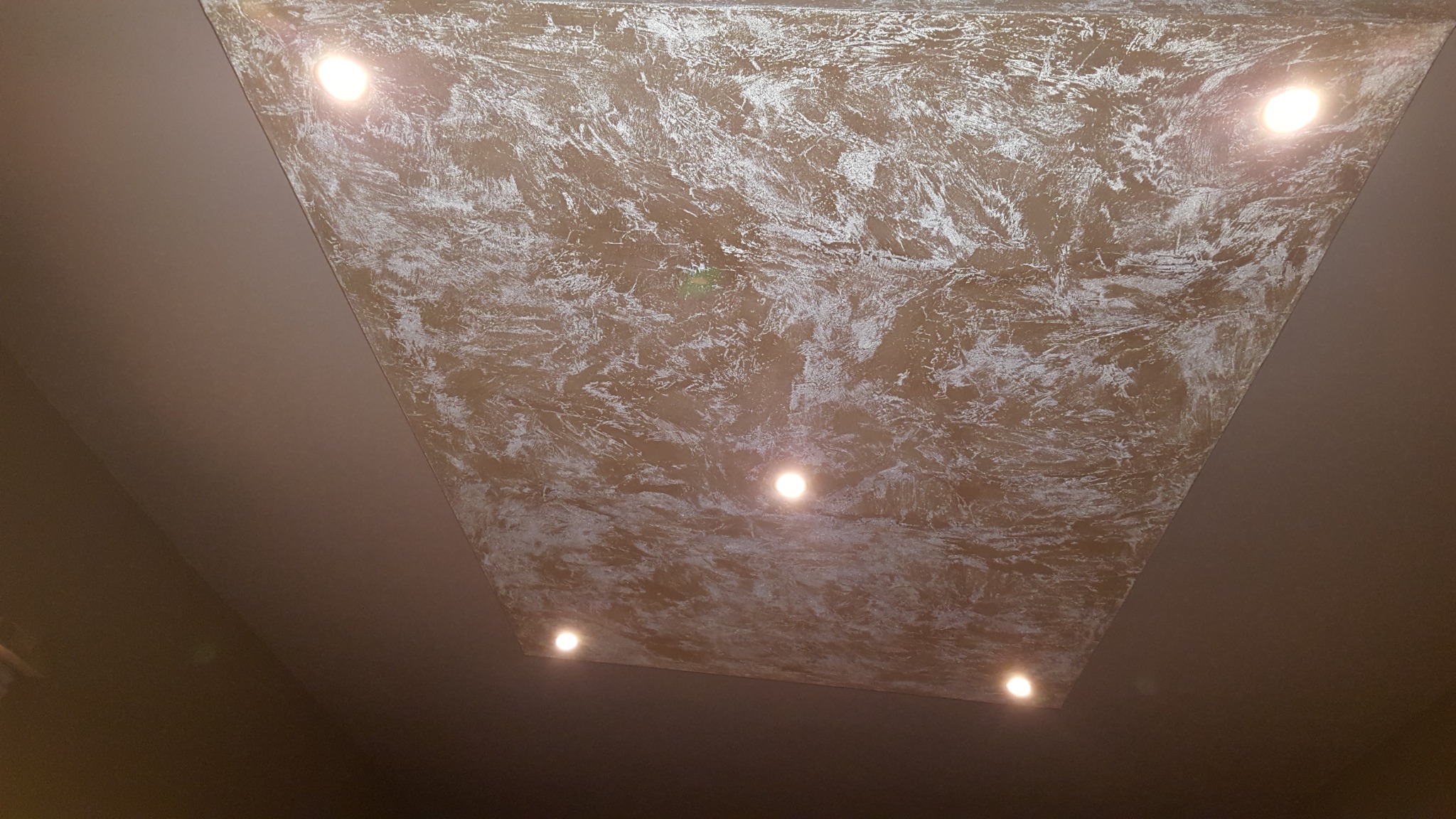 Dekoracyjny sufit podwieszany z beżową strukturą i białymi wzorami, oświetlony pięcioma punktowymi lampami LED