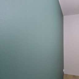 COMFORT HOME Sp. z o.o - Świeżo pomalowana ściana w odcieniach morskiej zieleni, kontrastująca z białą ścianą i sufitem w rogu pomieszczenia, widoczny fragment podłogi z paneli.