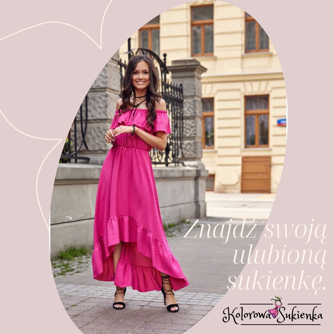 Uśmiechnięta kobieta w asymetrycznej sukience w kolorze fuksji z falbanami, czarnych sandałach na obcasie, stojąca na chodniku przed budynkiem z piaskowca i ozdobnym ogrodzeniem.