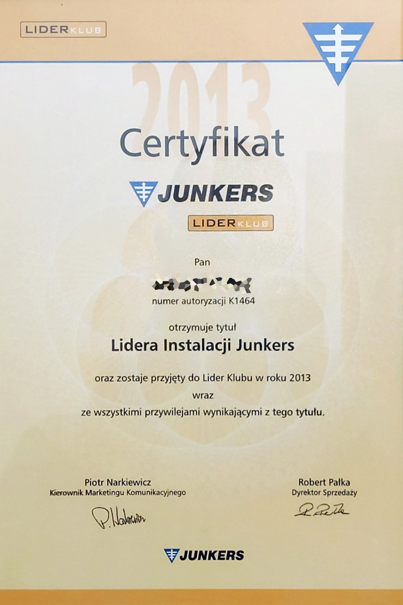 Certyfikat Lidera Instalacji Junkers z 2013 roku, z widocznymi podpisami Piotra Narkiewicza i Roberta Pałki, prezentowany na beżowym tle.