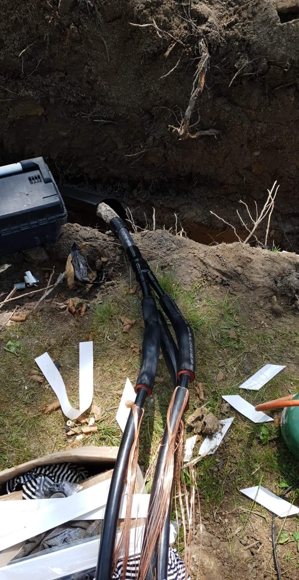 Kable energetyczne z miedzianymi żyłami wystające z wykopu w Jakubowie, widoczne narzędzia i resztki izolacji.