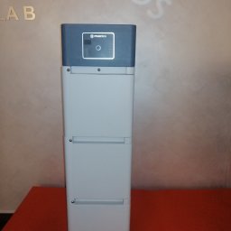 EMPA Sp z o.o - Pylontech modułowy magazyn energii w szarej obudowie, widoczne logo producenta i panel sterowania na tle jasnej ściany z napisem LAB i częściowo widocznym napisem 'INOUS'.