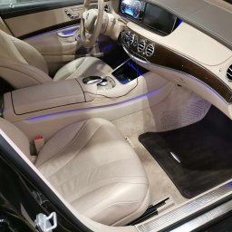 Monkey Showers - Wnętrze luksusowego samochodu Mercedes-Benz z jasną skórzaną tapicerką, drewnianymi akcentami i subtelnym podświetleniem LED, ukazujące dbałość o detale i elegancję.