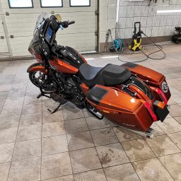 Monkey Showers - Pomarańczowo-czarny motocykl Harley-Davidson po umyciu, widoczny w garażu z myjką ciśnieniową w tle, na mokrej, kafelkowanej podłodze.