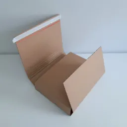 Rozłożone, tekturowe pudełko z widocznym paskiem klejącym i wewnętrzną strukturą falistą, leżące na białym tle.