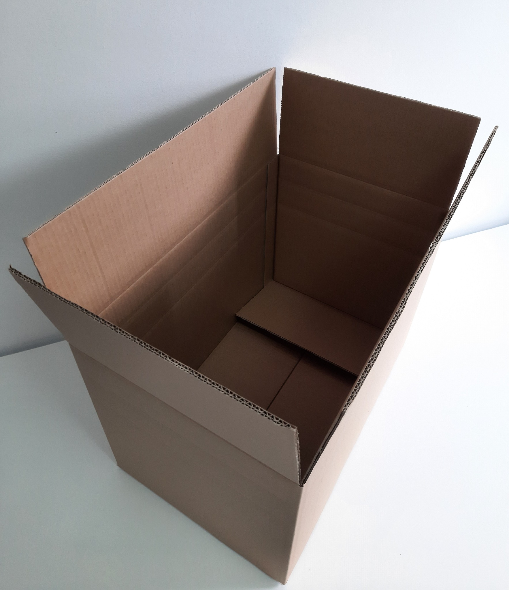 Otwarty, pusty karton z tektury falistej, widoczny od góry, z wewnętrzną przegródką na dnie, ustawiony na białym tle.