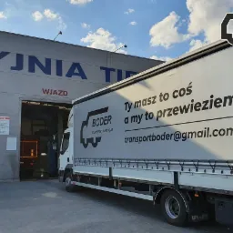 Ciężarówka z logo firmy transportowej 'Boder' na tle budynku myjni samochodowej z napisem 'MYJNIA TIR' i wjazdem.