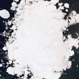 BIOKOM Sp. z o.o. Sp. komandytowa - Biały, krystaliczny proszek na ciemnym tle. Nawozy mineralne w formie granulatu, z bliska, tekstura i struktura. Fotografia makro.