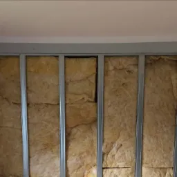 Wełna mineralna w metalowym stelażu, przygotowana do zabudowy płytami gipsowo-kartonowymi na poddaszu.