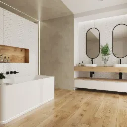 Nowoczesna łazienka z białą wanną, drewnianą półką w ścianie z kosmetykami, drewnianą podłogą i dwoma owalnymi lustrami nad umywalkami.