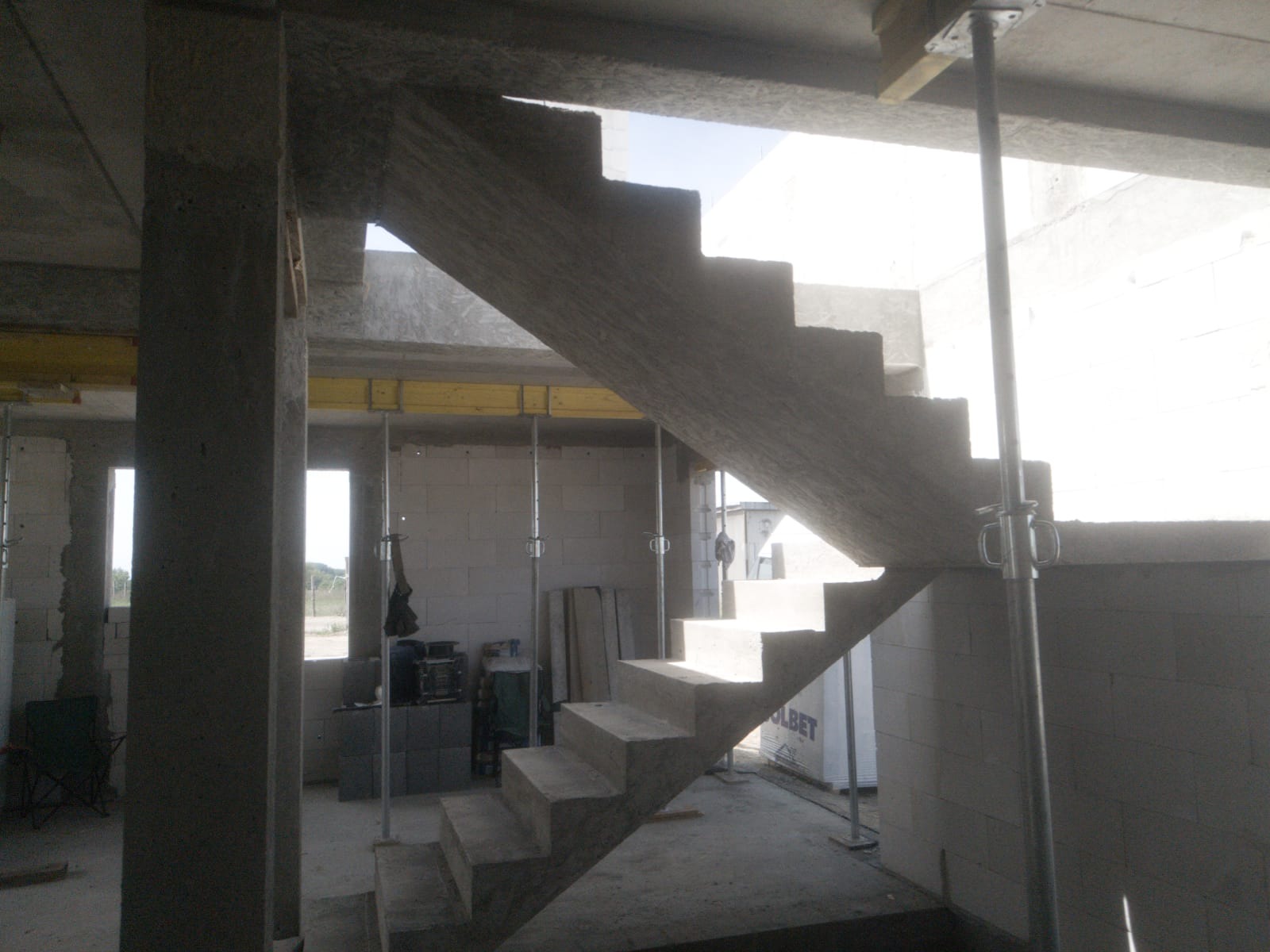 Wewnętrzne, żelbetowe schody w surowym stanie, podparte metalowymi stemplami, w trakcie budowy domu z bloczków.
