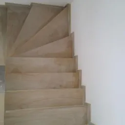 Kremowe, spiralne schody z kamienia, widok z g&oacute;ry, minimalistyczne wnętrze z białą ścianą.