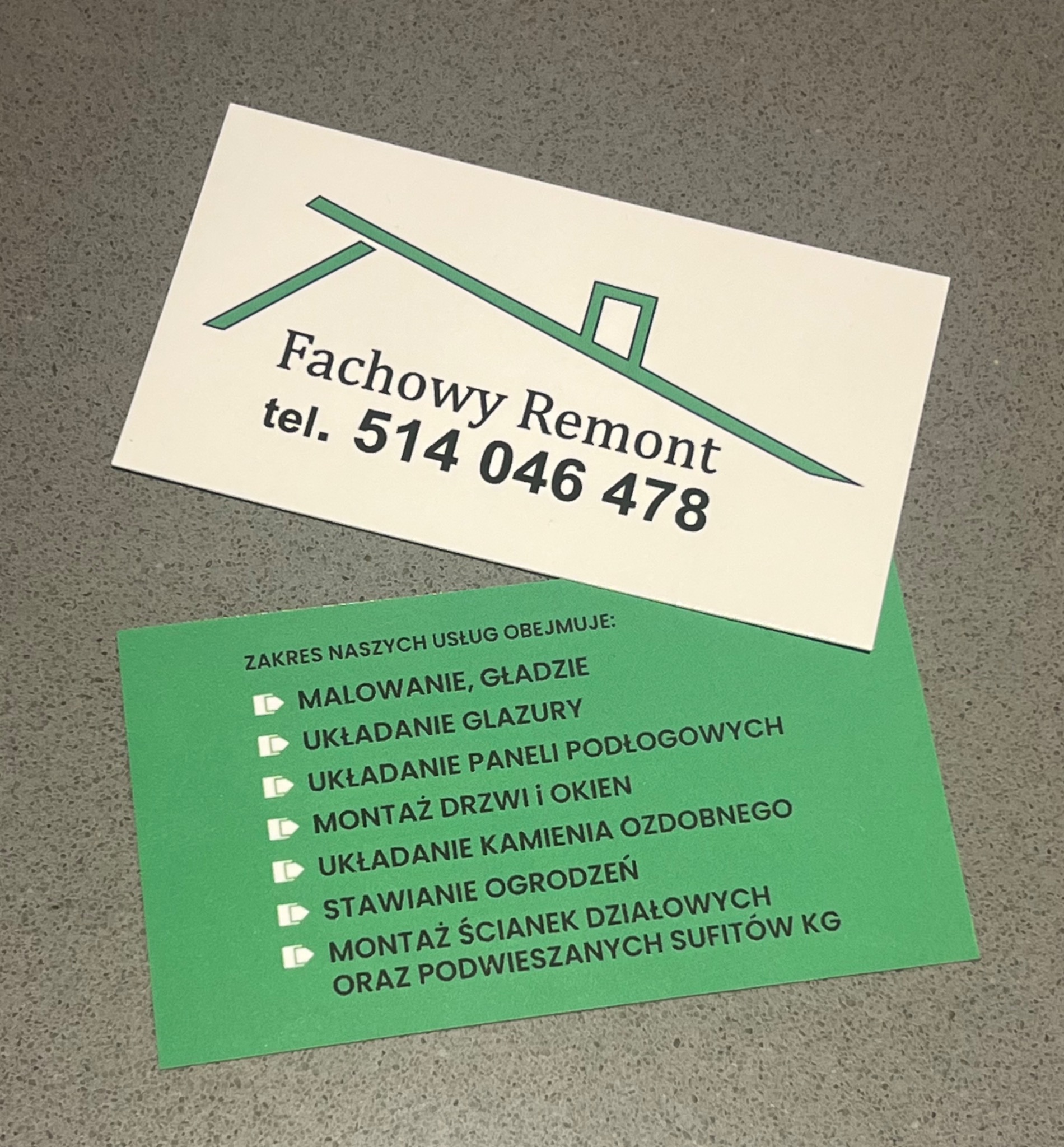 Dwie wizytówki firmy remontowej leżące na blacie. Górna wizytówka z zielonym symbolem dachu i napisem 'Fachowy Remont tel. 514 046 478'. Dolna, zielona wizytówka, wymienia zakres usług: malowanie...