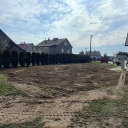 DSF Wyburzenia-Rozbiórki Dominik Filipek - Przygotowany teren pod budowę w Iwierzycach. Widoczne ślady opon po maszynach budowlanych, wyrównana ziemia, w tle zabudowa mieszkalna i linia tuj.