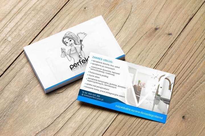 Wizytówka firmy sprzątającej z ilustracją kobiety z mopem i butelką ze spryskiwaczem, leżąca na drewnianym stole obok pudełka wizytówek z tym samym logo.