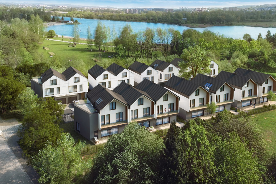 Nowoczesne szeregowe domy z ciemnymi dachami i jasnymi elewacjami, widok z góry, w tle jezioro i zieleń. Domy z balkonami i dużymi oknami.